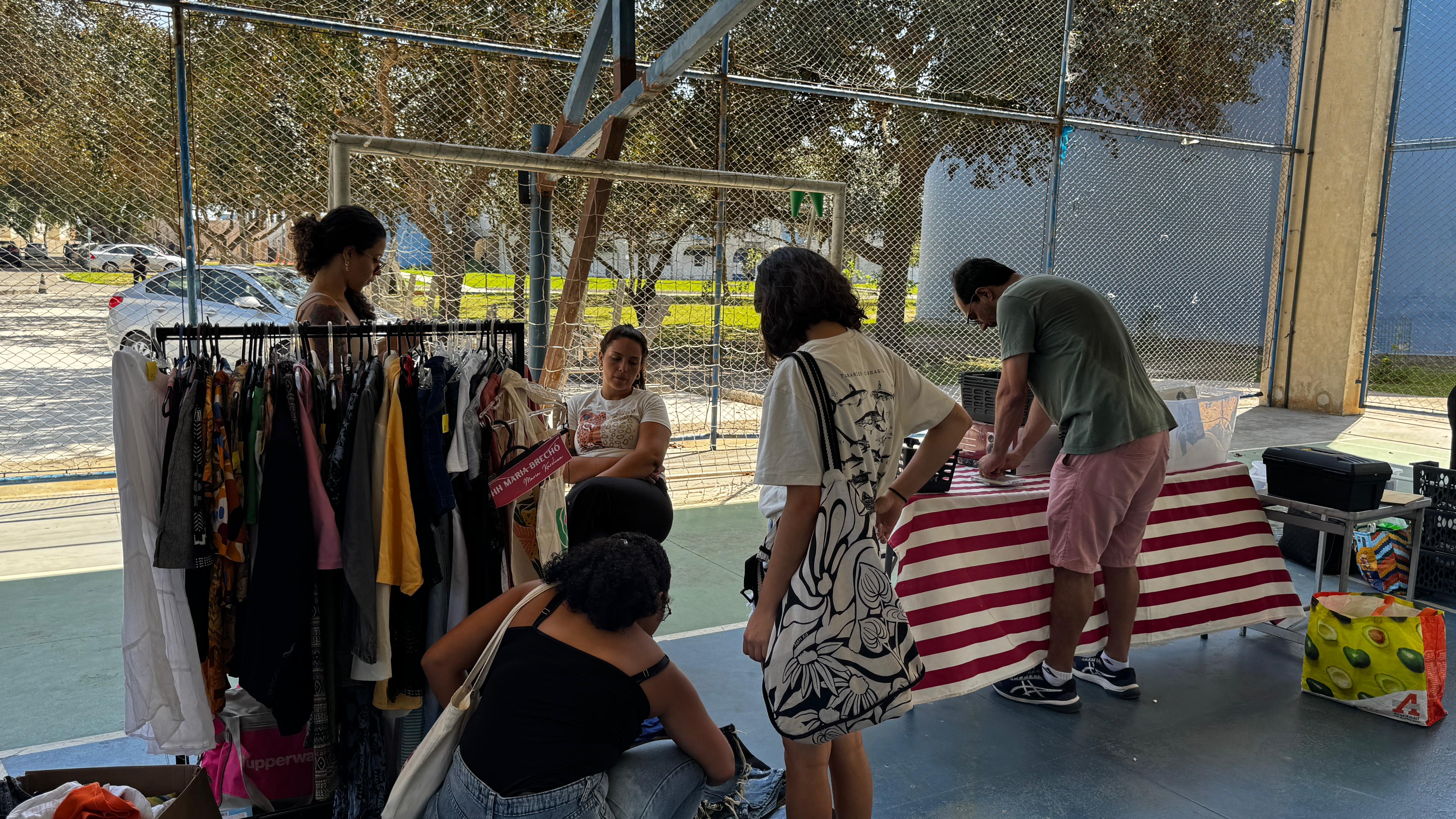 Pessoas olham artigos vendidos no brecho da Itep: Arara Coletiva